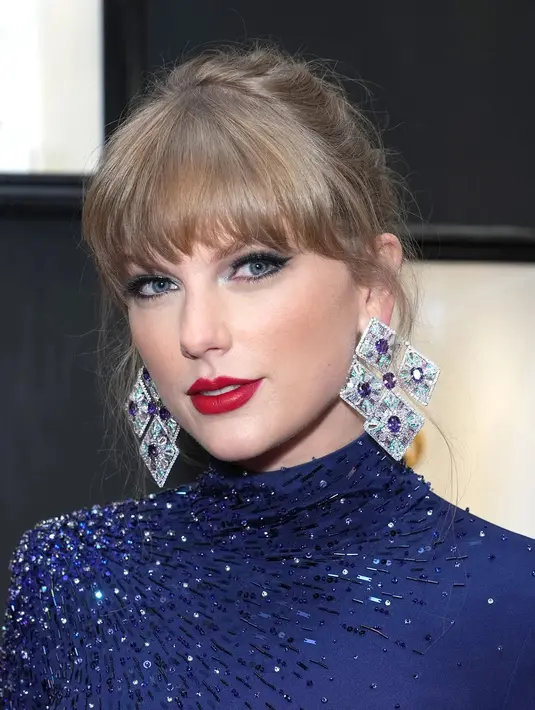 <p>Taylor Swift tampil dengan riasan bernuansa feminin. Ia tampil edgy dengan bibir merah yang terkesan kuat, eyeshadow biru, eyeliner tebal, dan poni penuhnya yang berantakan. Foto: Glamour.</p>