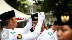Anggota pria paskibraka 2016 merapikan peci rekannya saat bersiap melaksanakan gladi bersih upacara HUT ke-71 Kemerdekaan RI di Istana Merdeka, Jakarta, Senin (15/8). (Liputan6.com/Faizal Fanani)
