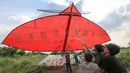 Warga menahan layang-layang merah putih raksasa sebelum diterbangkan di kawasan Bambu Apus, Tangerang Selatan, Senin (17/8/2020). Layangan dengan bahan bambu, kertas dan plastik tersebut diterbangkan dalam rangka memperingati HUT Ke-75 RI. (Liputan6.com/Fery Pradolo)