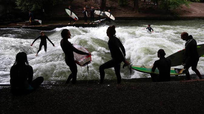 Seorang peselancar bermain ombak buatan di sungai 'Eisbach' di taman English Garden di Munich, Jerman, Kamis (16/7/2020). (AP Photo/Matthias Schrader)