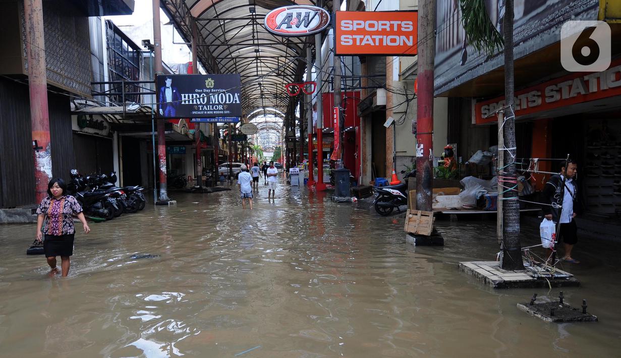 Warga melintas di kawasan pertokoan Pasar Baru, Jakarta, Kamis (2/1/2020). Pasca banjir yang melanda sejumlah titik di Jakarta pada Rabu (1/1), aktivitas perniagaan di kawasan Pasar Baru masih terlihat sepi dan sebagian toko masih tutup. (Liputan6.com/Helmi Fithriansyah)