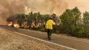 <p>Seorang petugas pemadam kebakaran berusaha memadamkan kebakaran hutan yang disebabkan suhu ekstrem di Larache, Maroko utara, Jumat (15/7/2022). Petugas pemadam kebakaran dan militer berjuang untuk menahan beberapa kebakaran hutan di Maroko utara, ketika ratusan warga mengungsi dari rumah mereka karena kobaran api yang melanda petak besar hutan pinus. (AP Photo)</p>