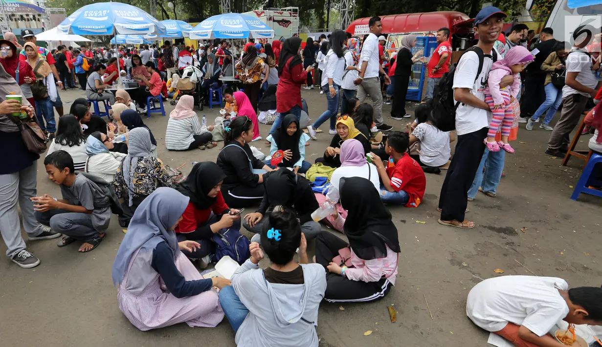 Pengunjung menikmati makan sambil lesehan jelang Closing Ceremony Asian Games 2018 di kawasan Gelora Bung Karno, Jakarta, Minggu (2/9). Mereka tidak mendapatkan kursi makan karena dipadati pengunjung. (Liputan6.com/Fery Pradolo)