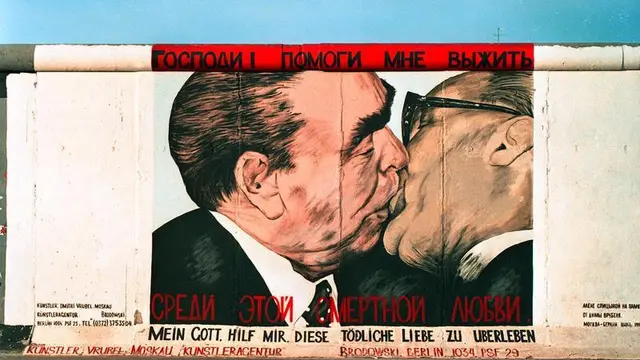 Mural Pemimpin Jerman Timur Erich Honecker berciuman dengan pemimpin Uni Soviet Leonid Brezhnev di Tembok Berlin pada masa Perang Dingin (Bundesarchiv/Joachim F Thurn via Wikimedia Commons)