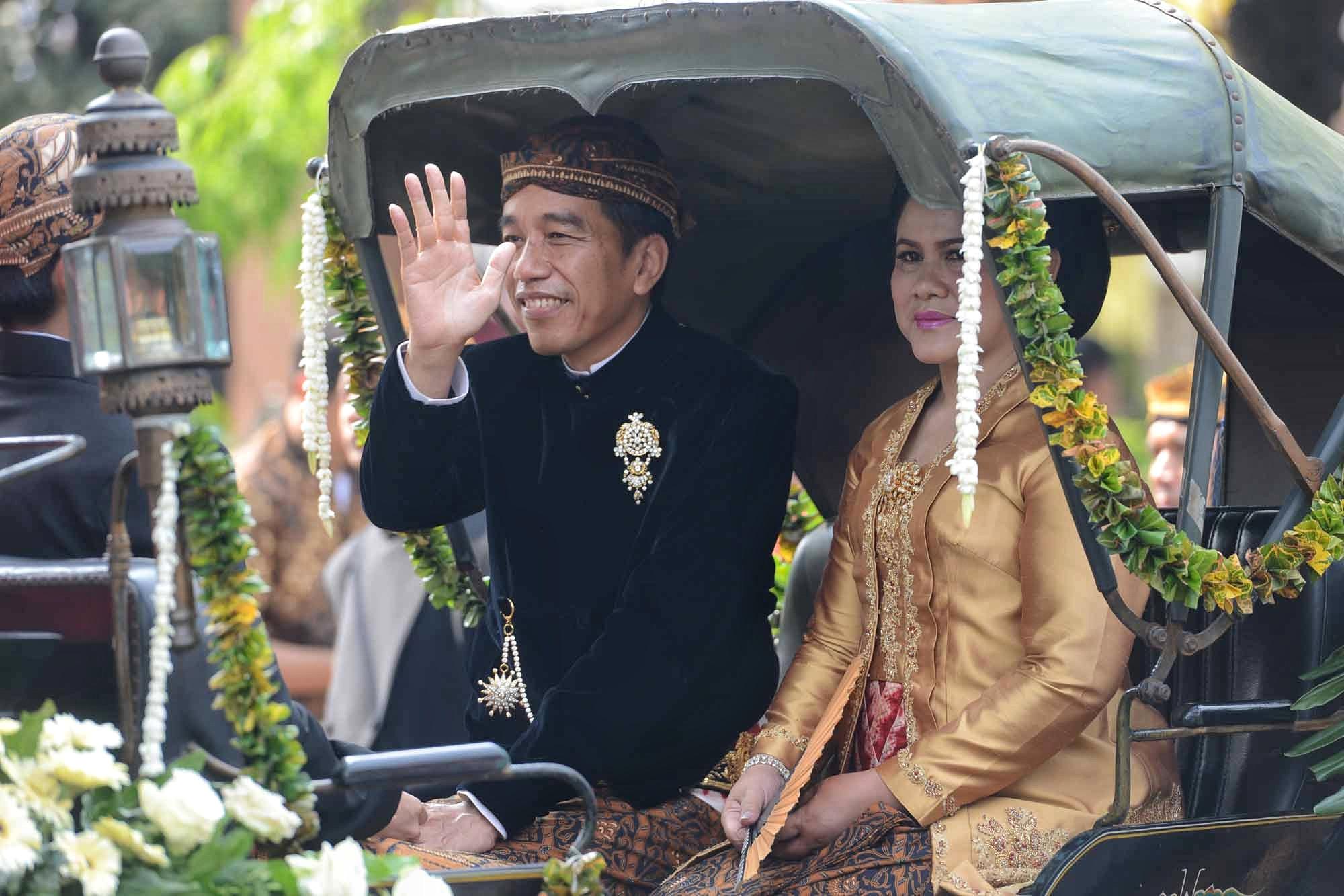 Dengan Kereta Kencana, rombongan keluarga besar Presiden Joko Widodo saat itu hendak menuju ke lokasi pernikahan Kahiyang dan Bobby di Graha Saba Buana. Lambaian tangan dan senyuman terus diberikan Jokowi. (Adrian Putra/Bintang.com)