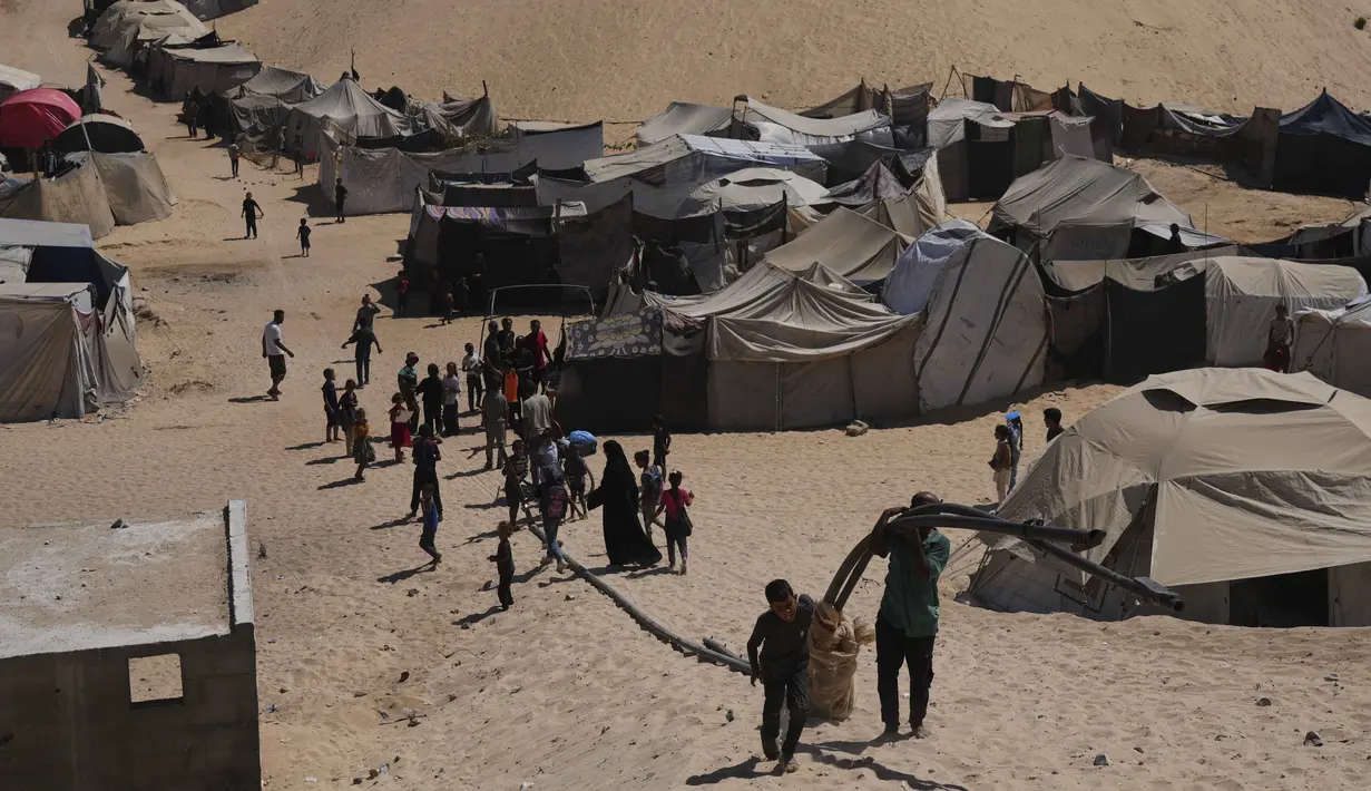 Pengungsi Palestina berjalan melalui kamp tenda di Muwasi, kawasan yang telah ditetapkan Israel sebagai zona aman, di Khan Younis, bagian selatan Jalur Gaza, Minggu 21 September 2025. (AP Photo/Jehad Alshrafi)