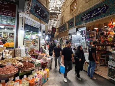 Orang-orang berjalan melewati toko-toko di Tajrish Bazaar, ibu kota Iran, Teheran, pada 30 Juni 2025. (ATTA KENARE/AFP)