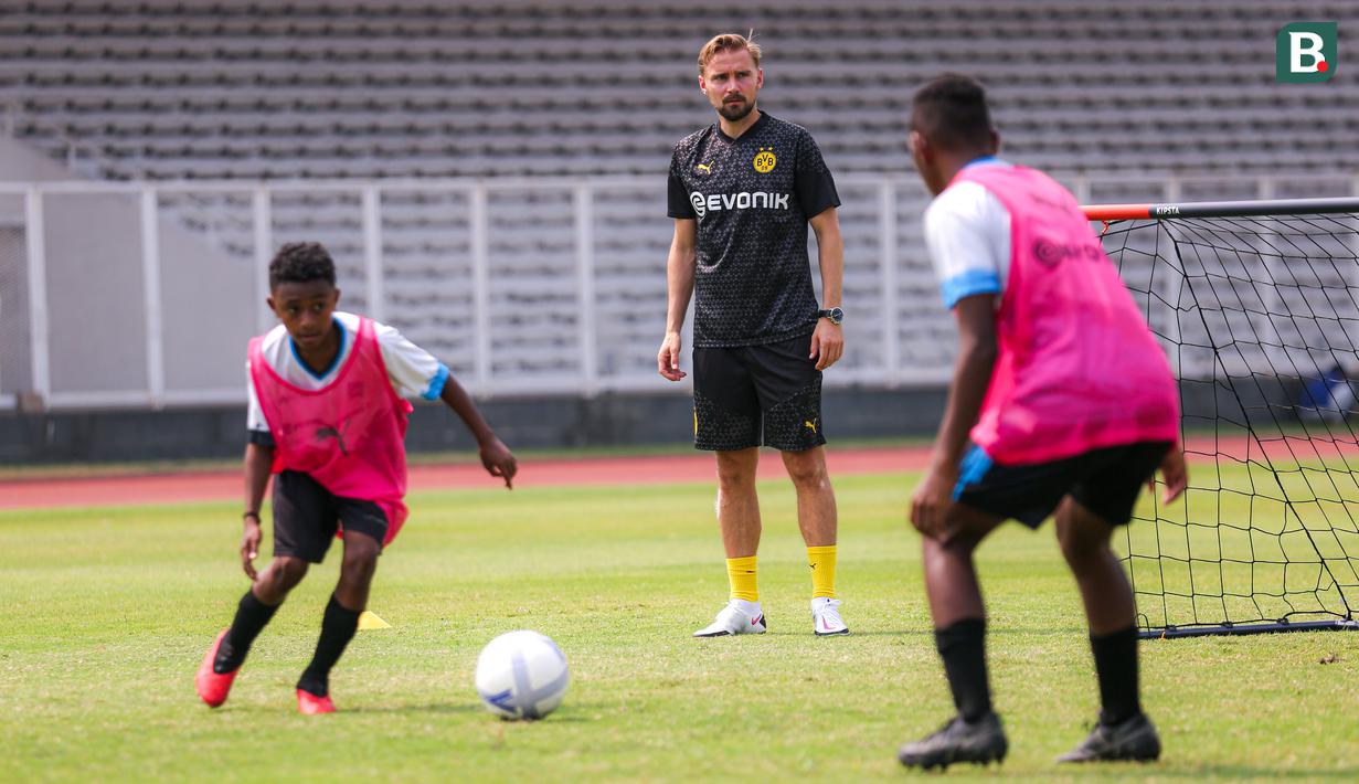 Legenda Borussia Dortmund, Marcel Schmelzer (tengah) memantau peserta coaching clinic dari Papua Football Academy di Stadion Madya, Senayan, Jakarta, Jumat (08/09/2023). (Bola.com/Bagaskara Lazuardi)