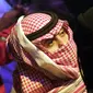 Seorang pria Saudi menggunakan keffiyeh tradisionalnya sebagai masker ketika ia menyaksikan pertandingan gulat WWE Super ShowDown di Riyadh, Arab Saudi, Kamis (27/2/2020). Arab Saudi menghentikan sementara izin umrah karena kekhawatiran tentang epidemi virus corona COVID-19. (AP Photo/Amr Nabil)