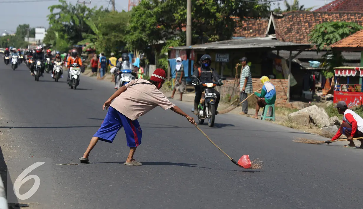 Penyapu jalan mengambil uang receh di kawasan Kabupaten Indramayu, Subang, Jawa Barat, Senin (11/7). Penyapu jalan atau yang di sebut Tawur sudah menjadi tradisi di jalur Pantura. (Liputan6.com/Herman Zakharia)