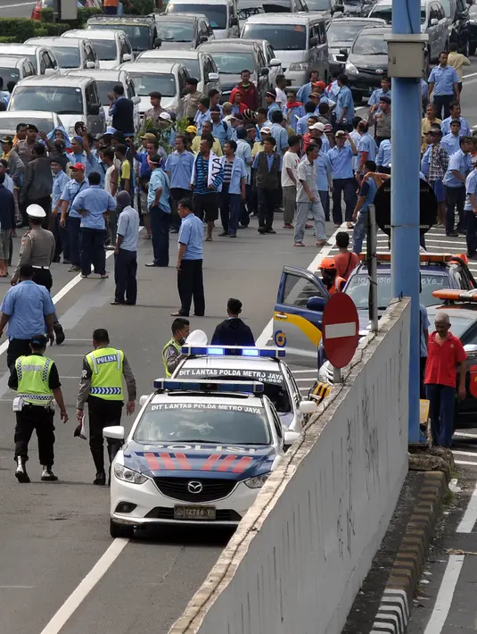 Petugas saat mengatur aksi demo supir taksi di dalam jalan tol Gatot Subroto, Jakarta, Selasa (22/3). Selain melakukan demo supir taxi tersebut melakukan sweeping ke sopir taksi yang beroperasi di dalam tol, dan membakar ban.(Liputan6.com/Johan Tallo)