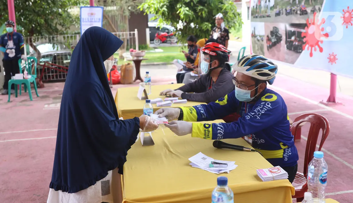 Petugas memberikan surat suara kepada warga yang akan menggunakan hak pilihnya dalam Pilkada 2020 di TPS 23 Pondok Jagung Timur, Tangerang Selatan, Rabu (9/12/2020). TPS Pilkada Tangsel itu menggunakan tema hobi dimana petugasnya mengenakan pakaian untuk bersepeda. (Liputan6.com/Angga Yuniar)