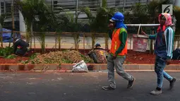 Pekerja melintasi dekat penataan jalur pedestrian di sepanjang Jalan Jenderal Sudirman - Jalan MH Thamrin, Jakarta, Selasa (10/7). Gubernur DKI Anies Baswedan menyatakan pelebaran trotoar itu  akan rampung Juli ini. (Merdeka.com/Imam Buhori)