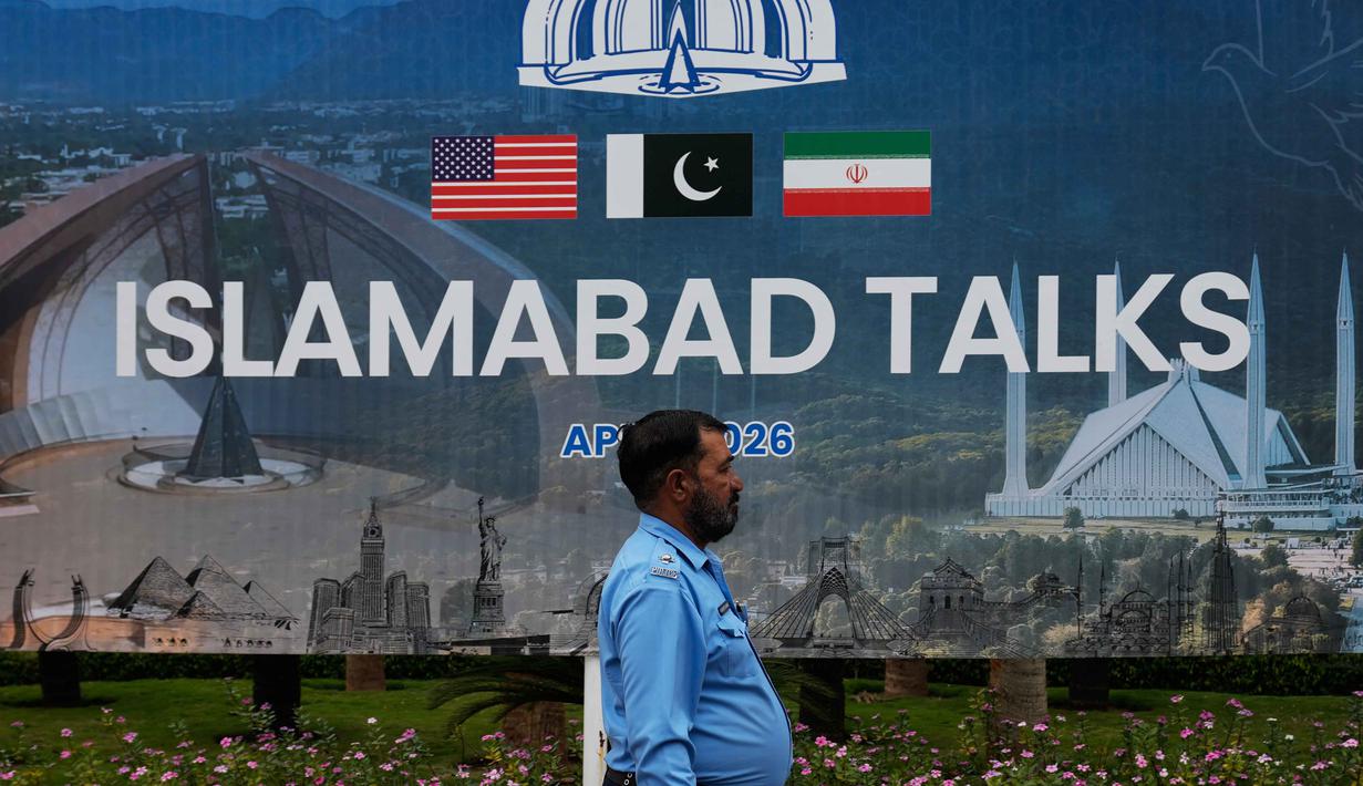 Diketahui, Amerika Serikat dan Iran saat ini berada dalam masa gencatan senjata selama dua minggu yang mulai berlaku sejak Rabu, 8 April 2026. Tampak dalam foto, seorang petugas polisi berjalan melewati papan reklame mengenai negosiasi Amerika Serikat dan Iran, di luar pusat fasilitasi media di Islamabad, Pakistan, Sabtu, 11 April 2026. (AP Photo/Anjum Naveed)