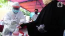 Petugas berpakaian baju hazmat menandai jari warga dengan tinta usai mencoblos dalam Pilkada Tangerang Selatan 2020 di TPS 46, Paku Jaya, Serpong Utara, Rabu (9/12/2020). Para petugas KPPS di TPS 46 ini mengunakan seragam APD untuk mengantisipasi penyebaran COVID-19. (merdeka.com/Arie Basuki)