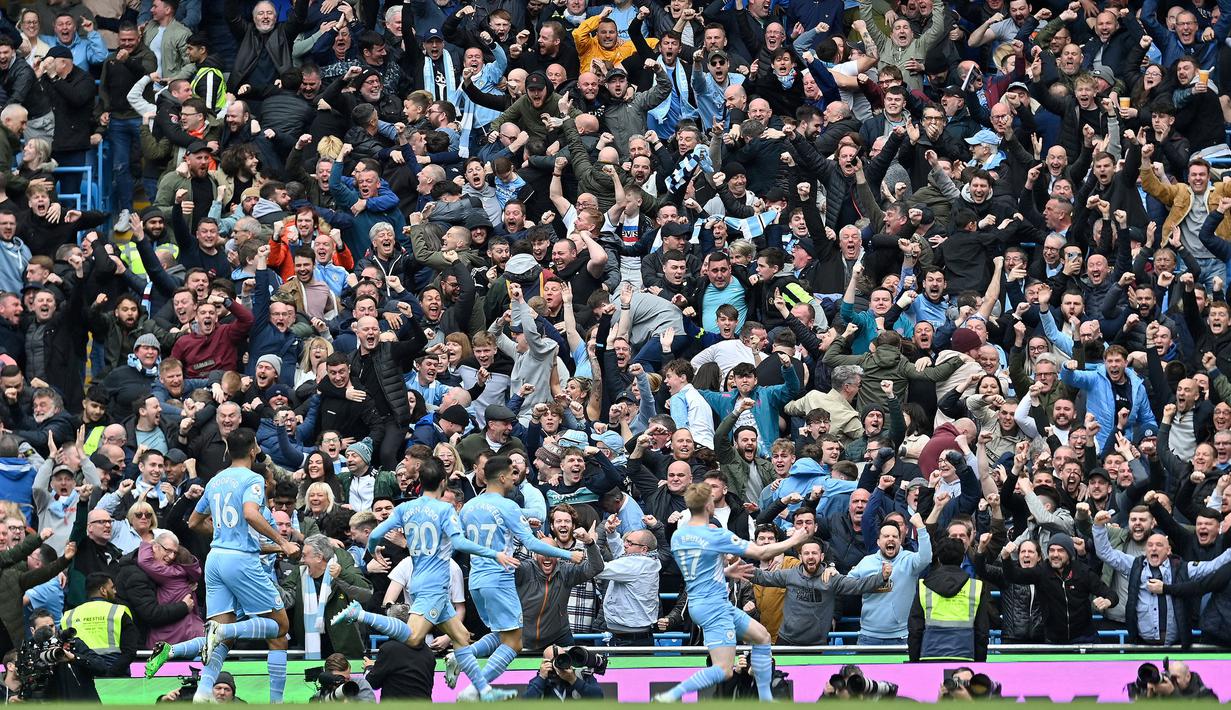 Fans Manchester City bersorak saat gelandang Manchester City dari Belgia, Kevin De Bruyne (kanan) merayakan gol pembuka saat pertandingan Liga Inggris antara Manchester City dan Liverpool di Etihad Stadium, 10 April 2022. (AFP/Paul Ellis)
