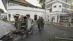 Personel keamanan berjalan melewati kendaraan yang terbakar di dekat kediaman resmi mantan perdana menteri Sri Lanka Mahinda Rajapaksa 'Temple Trees', sehari setelah diterobos oleh para pengunjuk rasa di Kolombo pada 10 Mei 2022. PM Sri Lanka Mahinda Rajapaksa mengundurkan diri di tengah gelombang demonstrasi massal yang memprotes cara pemerintah menangani krisis ekonomi. (ISHARA S. KODIKARA / AFP)
&nbsp;