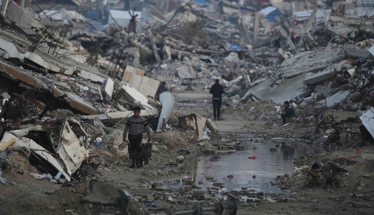 Menurut Direktur Operasi Komite Internasional Palang Merah (ICRC), Yasmine Praz Dessimoz, pembukaan kembali perlintasan di perbatasan Rafah sangat penting untuk menyediakan bantuan kemanusiaan dalam jumlah yang cukup ke Jalur Gaza. Tampak dalam foto, warga Palestina berjalan di tengah bangunan yang hancur akibat serangan udara dan darat Israel di Kota Gaza, Selasa 6 Januari 2026. (AP Photo/Jehad Alshrafi)