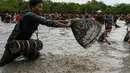 Penduduk desa menangkap ikan selama upacara penangkapan ikan tahunan di komune Choam Krovean di provinsi Tboung Khmum pada 18 Februari 2023. Dengan menggunakan keranjang bambu buatan tangan dan jaring nilon, ratusan orang mengarungi danau berlumpur setinggi paha di Kamboja timur pada hari Sabtu untuk upacara penangkapan ikan tahunan, di mana hanya alat-alat tradisional yang digunakan. (AFP/Tang Chhin Sotthy)