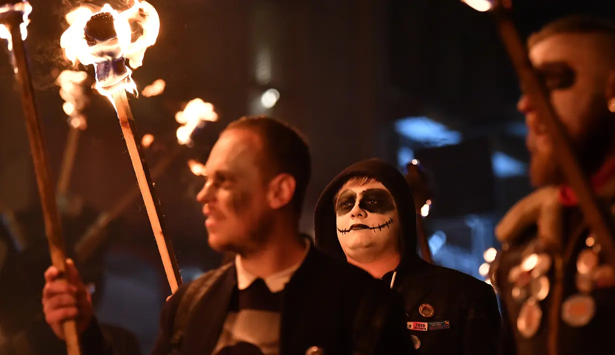 Peserta melakukan pawai sambil membawa obor dalam perayaan Bonfire Night melintasi jalan di Sussex Timur, Inggris, Selasa (5/11/2019). Obor yang mereka bawa itu nantinya akan digunakan untuk menyalakan kembang api dan api unggun. (Ben STANSALL/AFP)
