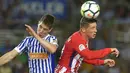 Striker Atletico Madrid, Fernando Torres, duel udara dengan bek Real Sociedad, Aritz Elustondo, pada laga La Liga di Stadion Municipal de Anoeta, Kamis (19/4/2018). Real Sociedad menang 3-0 atas Atletico Madrid. (AFP/Ander Gillenea)