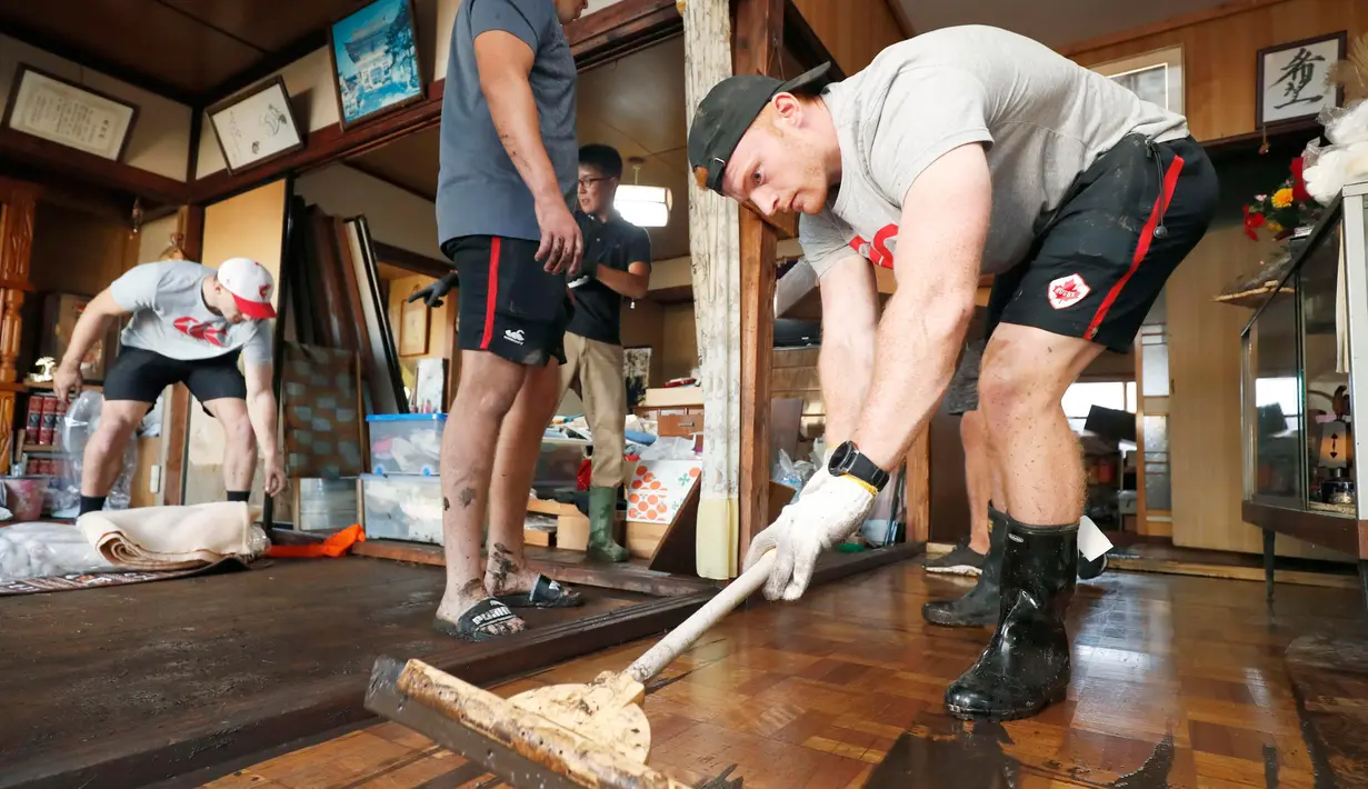Pemain rugby Kanada Peter Nelson secara sukarela membersihkan lumpur dari sebuah rumah di Kamaishi, Prefektur Iwate, Jepang, Minggu (13/10/2019). Topan Hagibis membuat pertandingan Rugby World Cup Pool B antara Kanada dengan Namibia dibatalkan. (Kyodo News via AP)