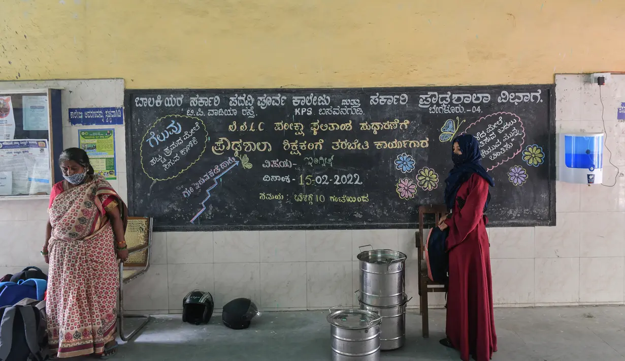Seorang siswa (kanan) berdiri selama salat Subuh di sekolah menengah negeri dan perguruan tinggi pra-universitas untuk wanita di Bangalore (16/2/2022). Pembukaan setelah pihak berwenang melarang pertemuan publik menyusul protes atas Muslim perempuan berhijab di kelas. (AFP/Manjunath Kiran)