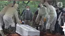 Petugas memakamkan jenazah Dedi Yuliardi Ashadi atau Dorce Gamalama di TPU Bantar Jati, Bambu Apus, Jakarta, Rabu  (16/2/2022). Dorce menghembuskan nafas terakhir di RSPP Simprug, Jakarta Selatan, Rabu (6/2) pukul 07.00 WIB, setelah mengalami koma selama tiga minggu. (Liputan6.com/Herman Zakharia)