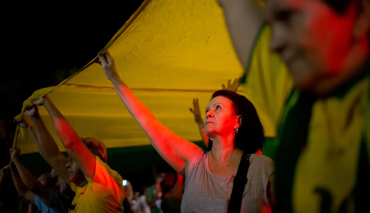 Sejumlah demonstran memegang spanduk dalam warna bendera Brasil untuk dibentangkan saat menggelar aksi protes di Rio de Janeiro, Brasil (3/4). Mereka menggelar aksi protes terkait mantan Presiden Brasil Luiz Inacio Lula da Silva. (AP / Silvia Izquierdo)