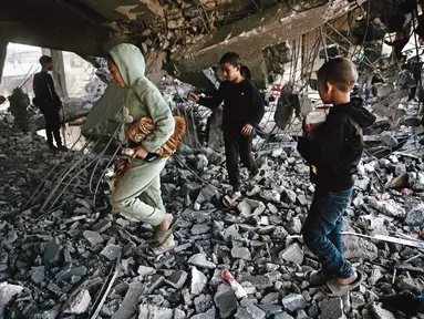 Anak-anak Palestina memeriksa puing-puing bangunan yang rusak milik Kementerian Wakaf Agama, yang digunakan sebagai tempat penampungan bagi pengungsi di kawasan Zeitoun, Kota Gaza, pada Kamis 20 November 2025, sehari setelah bangunan tersebut menjadi sasaran serangan militer Israel. Militer Israel kembali melancarkan rangkaian serangan ke sejumlah wilayah Gaza pada Rabu (19/11/2025). (Omar AL-QATTAA/AFP)