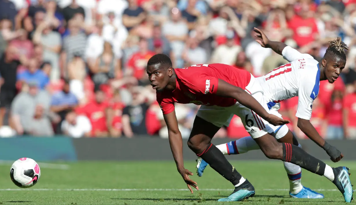 Gelandang Manchester United, Paul Pogba, berebut bola dengan striker Crystal Palace, Wilfried Zaha, pada laga Premier League di Stadion Old Trafford, Manchester, Sabtu (24/8). MU kalah 1-2 dari Palace. (AFP/Lindsey Parnaby)