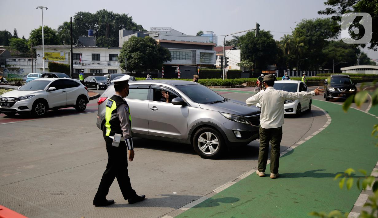 Petugas polisi mengarahkan kendaraan berplat nomor genap di pos penyekatan ganjil-genap di Bundaran Senayan, Minggu (5/9/2021). Pembatasan kendaraan dengan sistem pelat nomor kendaraan ini tetap berlaku di akhir pekan, Sabtu dan Minggu. (Liputan6.com/Angga Yuniar)