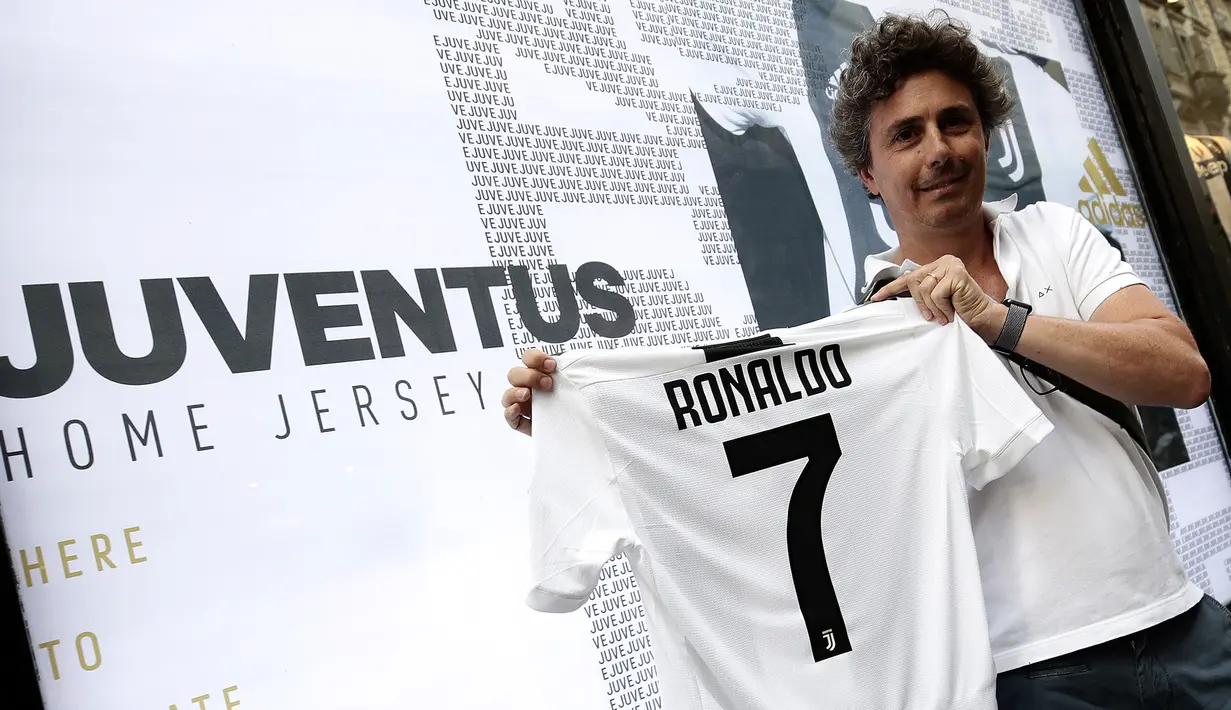 Seorang suporter, Giuseppe Strata memperlihatkan jersey Juventus atas nama Cristiano Ronaldo di depan toko resmi klub di Turin, Selasa (10/7). Berdasarkan rilis resmi dari pihak klub, Ronaldo diikat kontrak empat musim. (AFP PHOTO / Isabella Bonottovv)