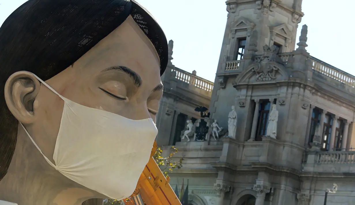 Patung raksasa yang akan ditampilkan di festival Las Fallas atau festival api terlihat mengenakan masker di Valencia, Spanyol, Rabu (11/3/2020). Festival Fallas yang akan berlangsung pada 13 Maret telah dibatalkan karena wabah coronavirus. (AFP/Jose Jordan)