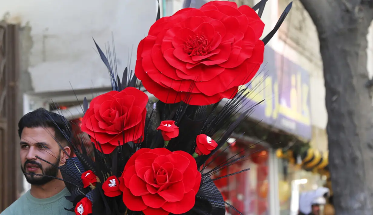 Seorang pria membawa buket mawar buatan untuk merayakan Hari Valentine di Kabul, Afghanistan, Minggu (14/2/2021). Hari Valentine menjadi budaya baru dalam masyarakat Afghanistan yang konservatif. (AP Photo/Rahmat Gul)