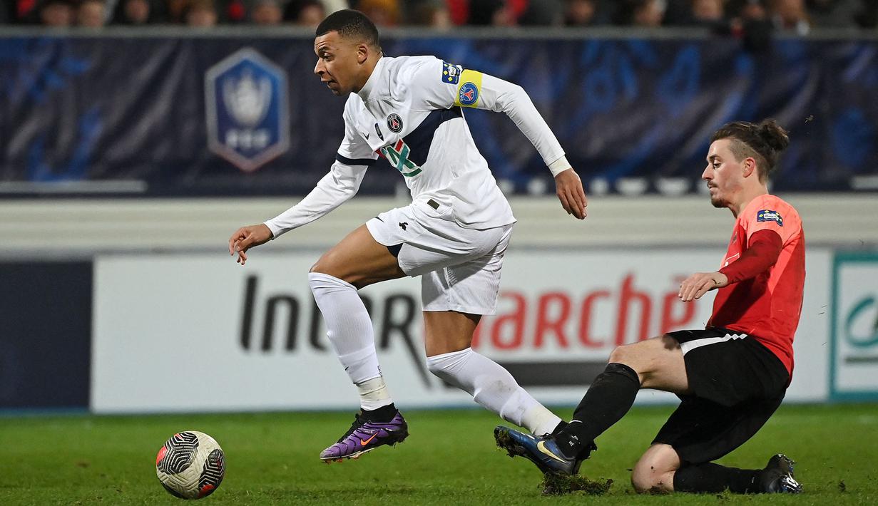 Pemain PSG, Kylian Mbappe (kiri) menggiring bola dibayangi pemain Revel, Pierre Ritter pada laga Piala Prancis 2023/2024 di Pierre-Fabre stadium, Castres, Prancis, Senin (08/01/2024) dini hari WIB. (AFP/Valentine Chapuis)