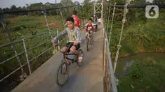 Anak-anak bersepeda melintasi jembatan gantung di Kelurahan Curug, Bojongsari, Kota Depok, Jawa Barat, Senin (24/8/2020). Setiap sore, warga sekitar bermain di jembatan tersebut sambil menikmati matahari tenggelam. (merdeka.com/Dwi Narwoko)