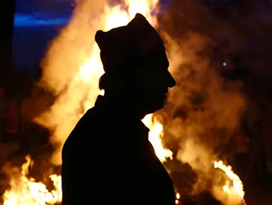 Siluet seorang pria saat mengikuti perayaan membakar jerami Ghanta Karna di Bhaktapur di pinggiran Kathmandu, Nepal (21/7). Festival Hindu in juga dikenal dengan nama Gathemangal. (AFP Photo/Gopen Rai)