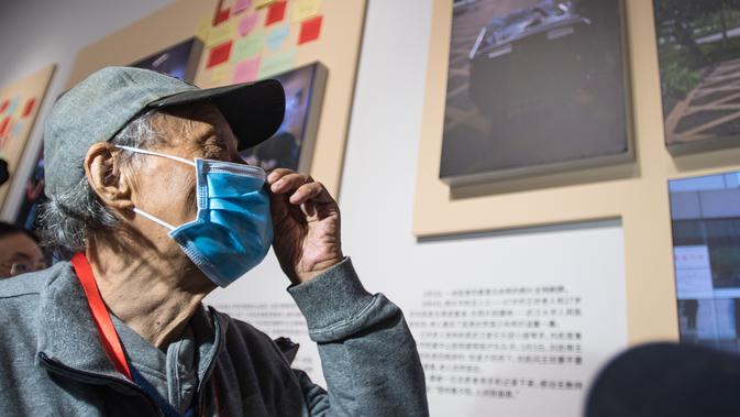 Wang Xin, warga yang sembuh dari COVID-19, melihat foto dirinya menikmati matahari terbenam saat masih menjadi pasien bersama seorang staf medis, yang menjadi viral di internet, dalam pameran perjuangan China melawan epidemi COVID-19 di Wuhan, Provinsi Hubei, China (15/10/2020). (Xinhua/Xiao Yijiu)