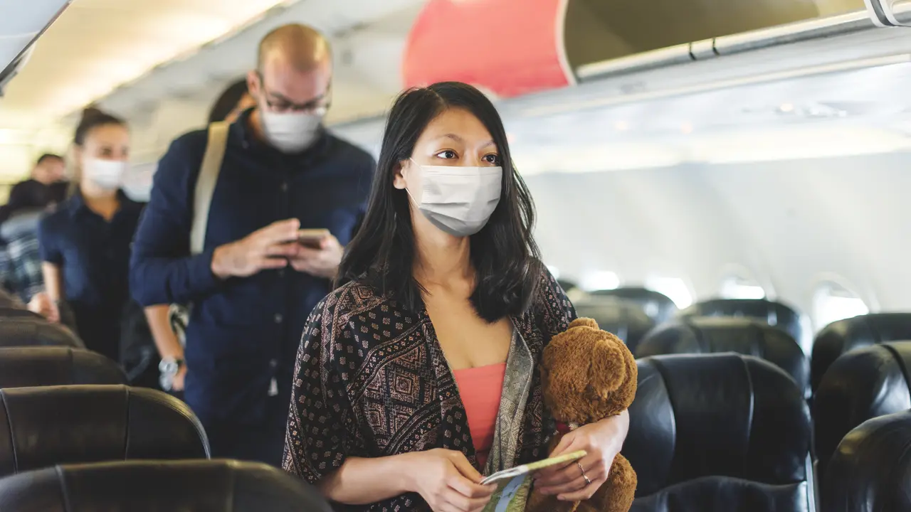perempuan memakai masker naik pesawat
