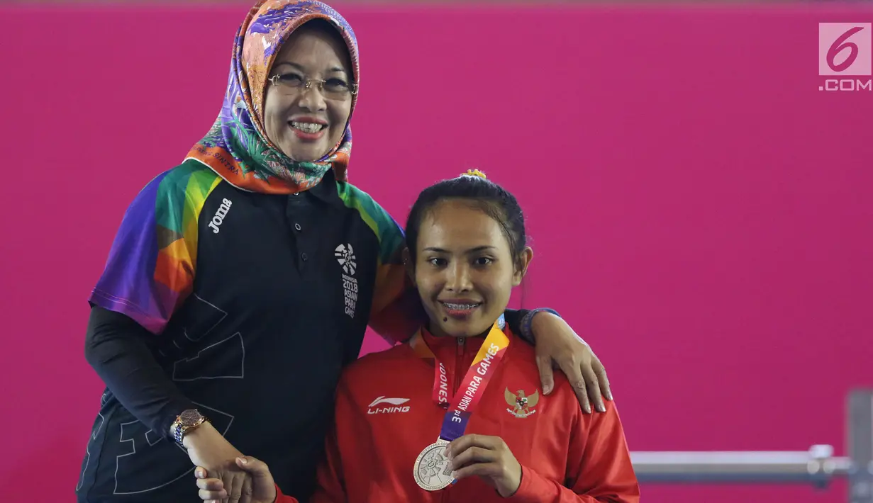 Atlet Para Powerlifting Indonesia, Ni Nengah Widiasih (kanan) saat prosesi medali Womens Up to 41.00kg Asian Para Games 2018 di Jakarta, Minggu (7/10). Ni Nengah Widiasih berhasil melakukan total angkatan 97 kg. (Liputan6.com/Helmi Fithriansyah)