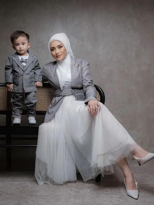 Bersama putranya, ia tampil dengan kerudung putih model segi empat yang dililitakn ke lehernya, Ia pun memoles wajanya dengan nuansa kecoklatan terlihat dari blush on, lipstik, dan riasan matanya. @nathalieholscher