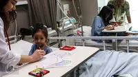 Seorang dokter membimbing pasien anak untuk mewarnai kertas bergambar telur Paskah di Rumah Sakit Siloam, Jakarta, Minggu (27/3). Kegiatan mewarnai gambar telur tersebut untuk menghibur pasien yang bertema "Stress Relief". (Liputan6.com/Fery Pradolo)