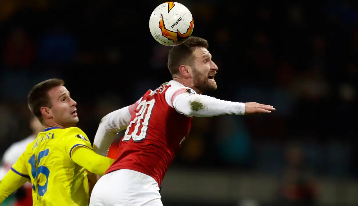 Pemain Arsenal Shkodran Mustafi berusaha merebut bola dari pemain BATE Borisov, Maksim Skavysh pada leg pertama 32 besar Liga Europa di Borisov Arena, Kamis (14/2). Arsenal kalah dengan skor 0-1 saat bertandang ke markas Bate Borisov. (AP/Sergei Grits)