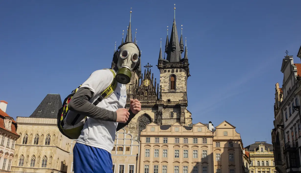 Seorang pria dengan masker gas berjalan melintasi Old Town Squaretempat kegiatan terhenti karena penyebaran virus corona baru di Praha pada 18 Maret 2020. Masker dijadikan masyarakat pilihan untuk mencegah penyebaran virus corona yang terus meningkat di seluruh dunia.  (Michal Cizek/AFP)