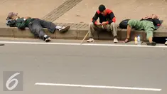 Massa aksi damai beristirahat di pinggir Jalan Merdeka Barat jelang bergerak menuju Istana Negara, Jakarta, Jumat (4/11). Massa melakukan aksi di depan Istana Negara menuntut penegakan hukum kasus dugaan penistaan agama. (Liputan6.com/Helmi Fithriansyah)