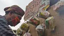 Seniman wayang uwuh, Iskandar Hardjodimuljo menggantungkan paket bahan makanan di jalan Cawang Baru Utara, Jakarta, Sabtu (18/4/2020). Paket sembako gratis itu inisiatif untuk menyisihkan hasil penjualan wayang uwuh yang terbuat dari sampah plastik dan kardus bekas. (Liputan6.com/Herman Zakharia)