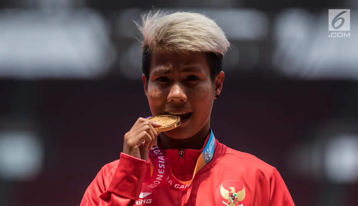 Atlet lompat jauh Indonesia, Rica Oktavia menggigit medali emas Asian Para Games 2018 di SUGBK, Jakarta, Senin (8/10). Rica menorehkan lompatan mencapai 5,25 meter. (Bola.com/Vitalis Yogi Trisna)