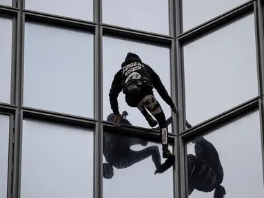 Pendaki Alain Robert atau French Spiderman memanjat Menara Total di kawasan bisnis La Defense, Paris, Prancis, Senin (13/1/2020). Alain memanjat gedung 48 lantai tersebut sebagai dukungan untuk pekerja yang mogok karena menentang reformasi pensiun di Prancis. (Thomas SAMSON/AFP)