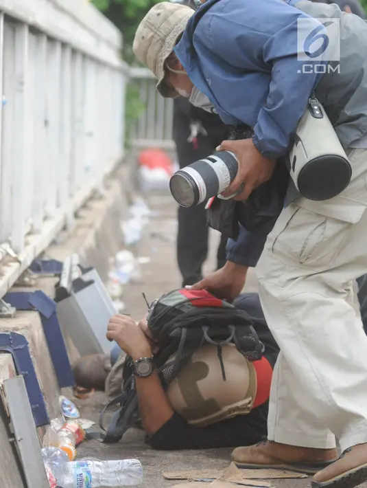 Jurnalis melindungi dirinya saat meliput demontrasi yang memanas di depan gedung Dewan Perwakilan Rakyat (DPR), Senayan, Jakarta, Selasa (24/9/2019). Polisi menembakkan gas air mata dan meriam air untuk membubarkan massa aksi yang menolak RKUHP dan RUU kontroversial lain. (merdeka.com/Arie Basuki)